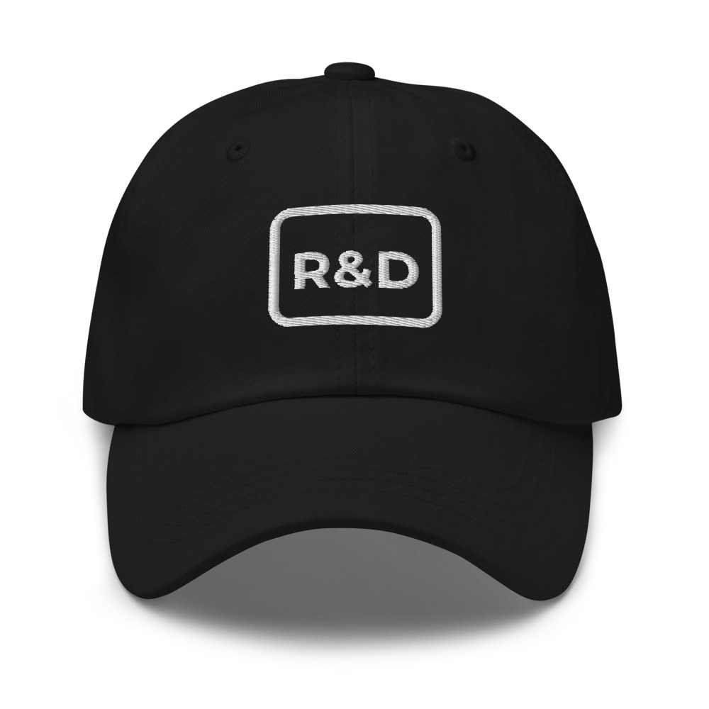 A black cap embroidered with the R&D service mark in a white rounded square.